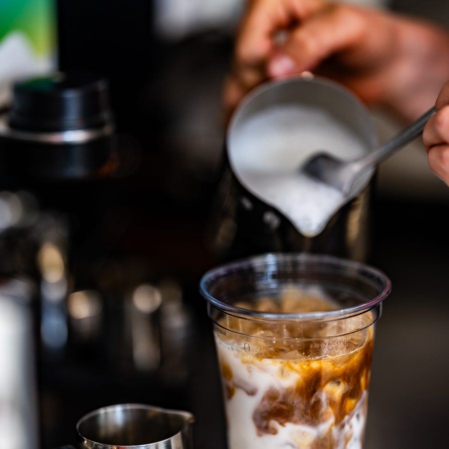 Milk being poured over iced coffee.