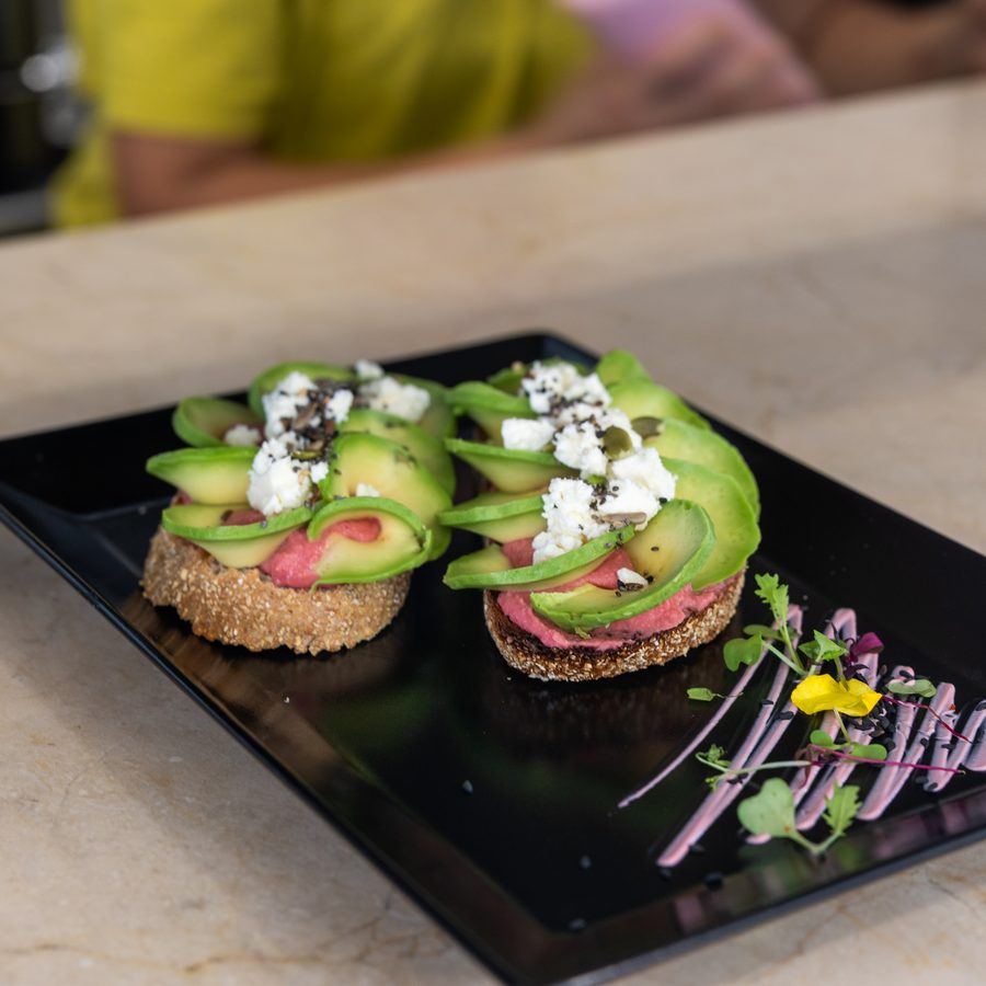 Smashed avocado on sourdough, seen from above with chilli and sprouts.