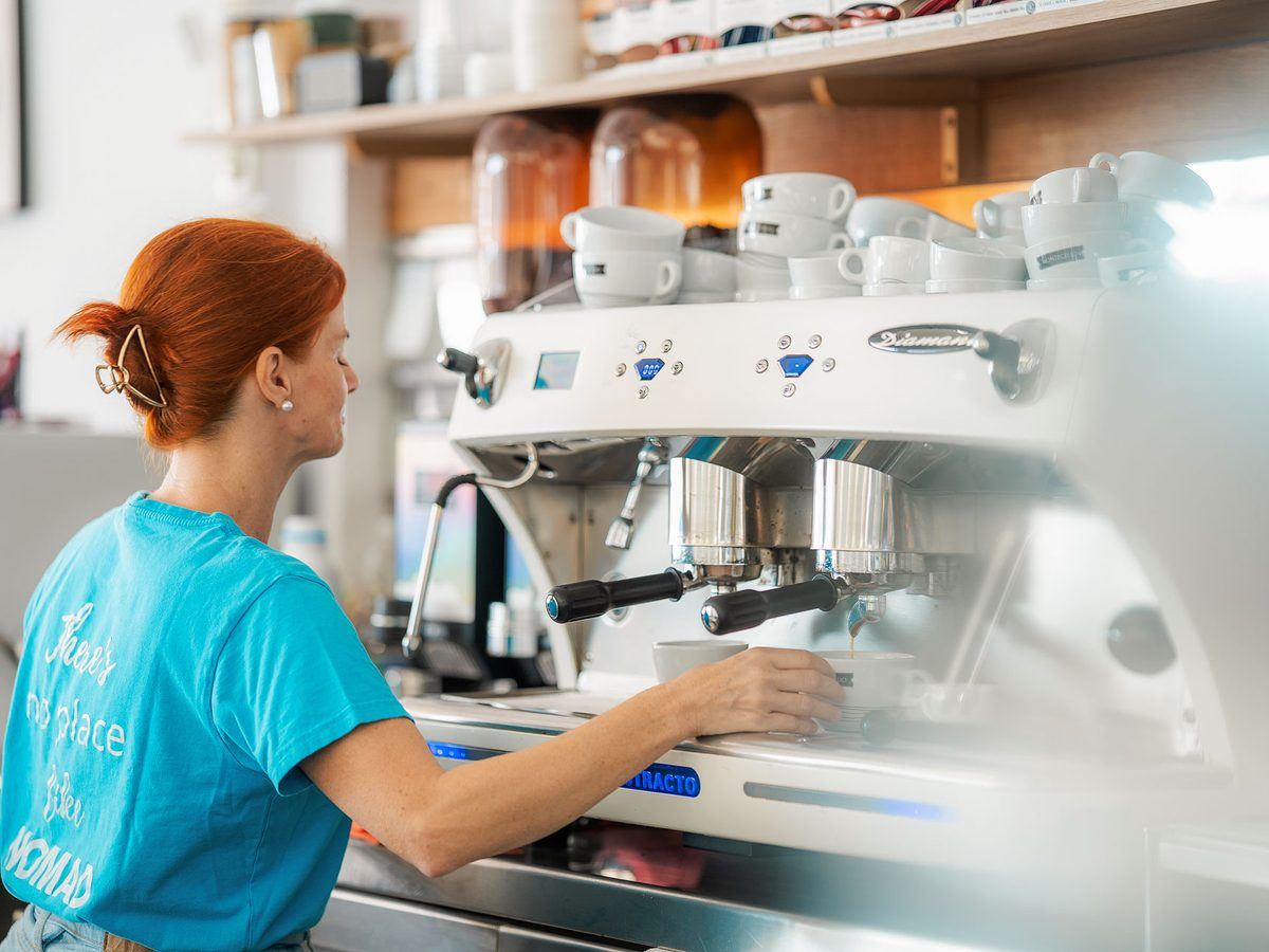 A barista pulling a coffee behind the machine.